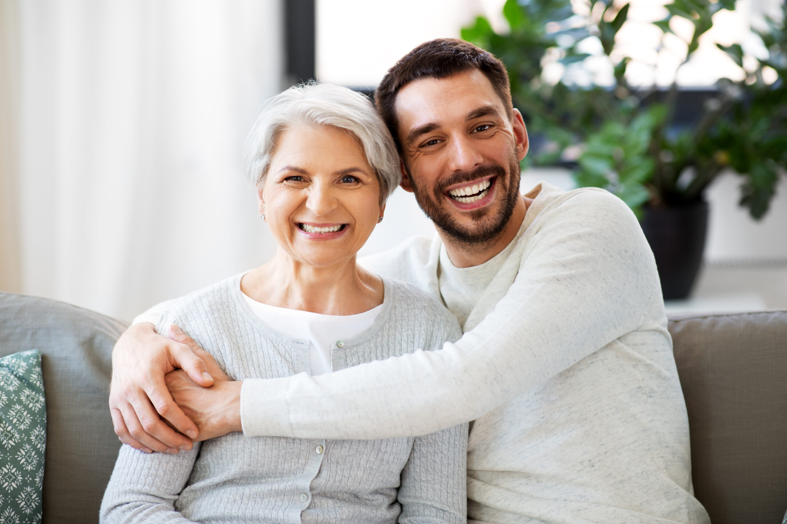 senior mother with adult son hugging at home