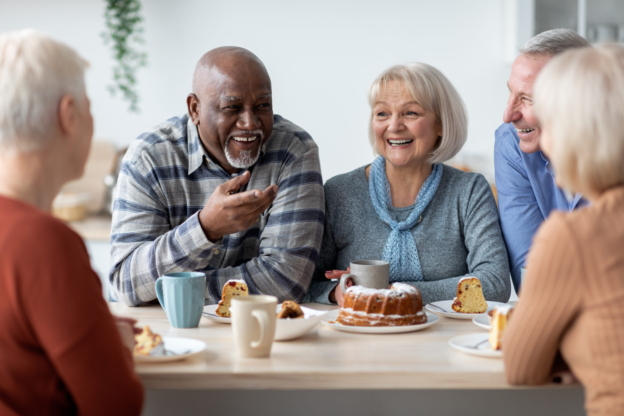 International group of positive elderly people drinking tea with cake